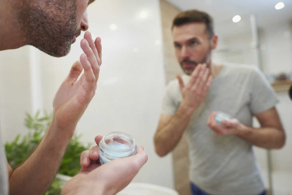 Man applying beauty product in the bathroom