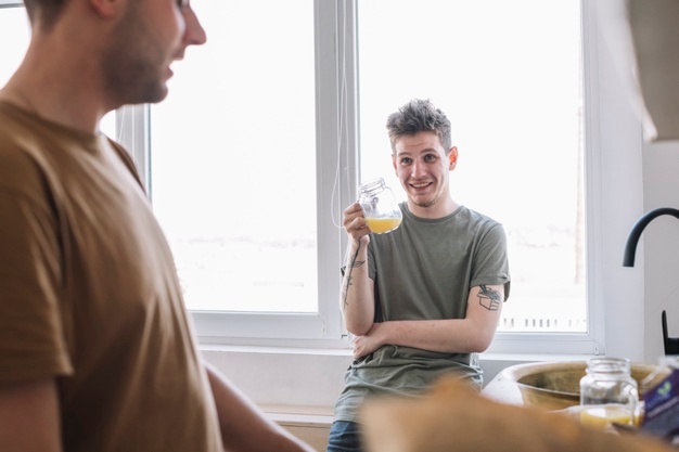 Two smiling friends sitting near window holding coffee cup