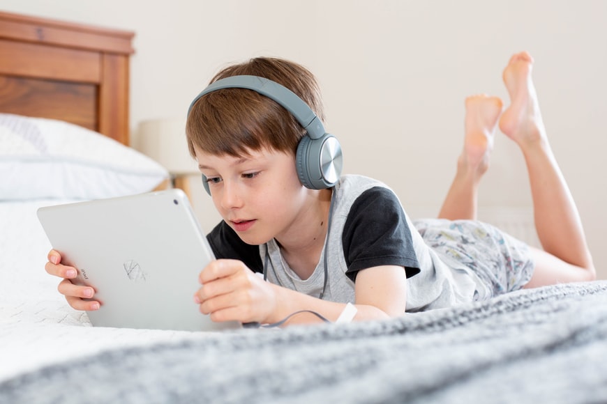 Boy using iPad with headphones on