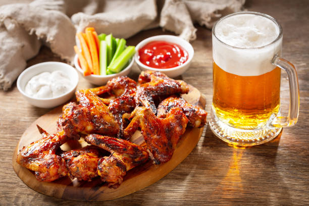 grilled chicken wings and mug of beer on a wooden board
