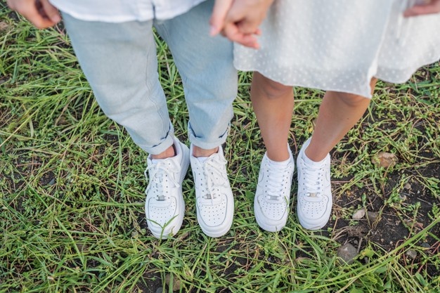 Couple standing on grass field. feet and shoes of young couple