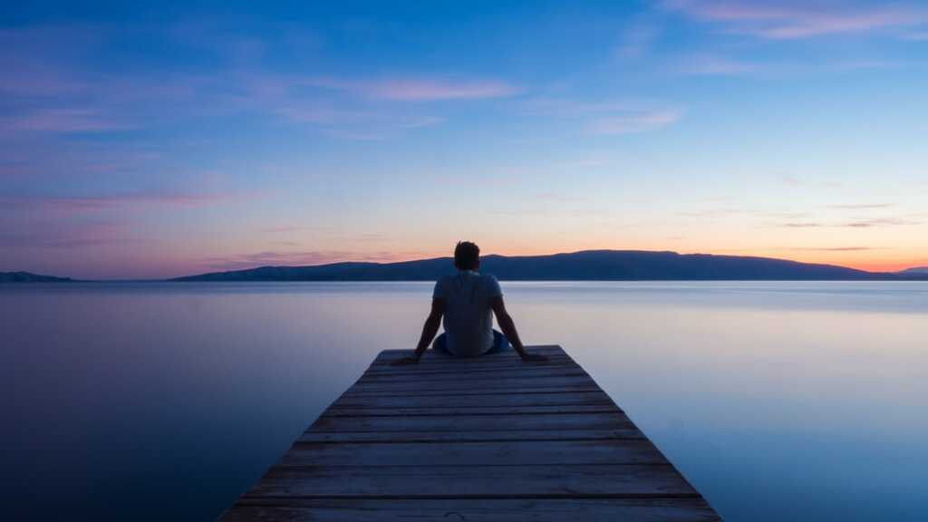 man sitting on a wooden bridge