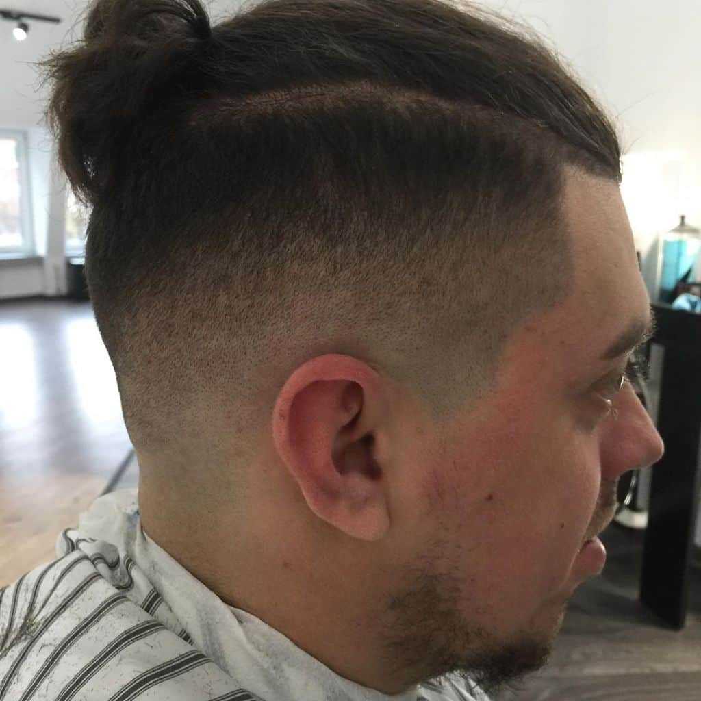 A-man-bun-hairstyle-paired-with-undercut-and-taper-fade.-A-standout-look-for-stylish-men