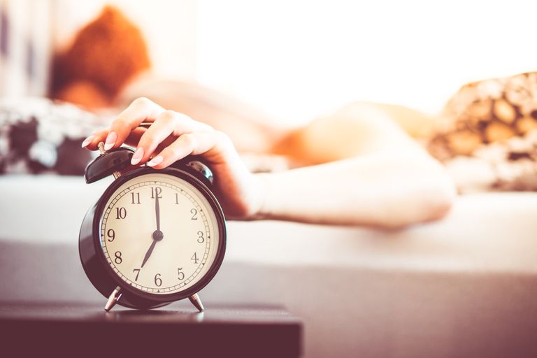 woman-shutting-off-ringing-alarm-clock