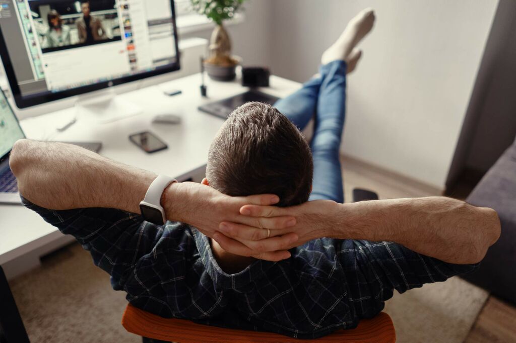 Modern Man in Home Office Relaxing with Legs on the Table 