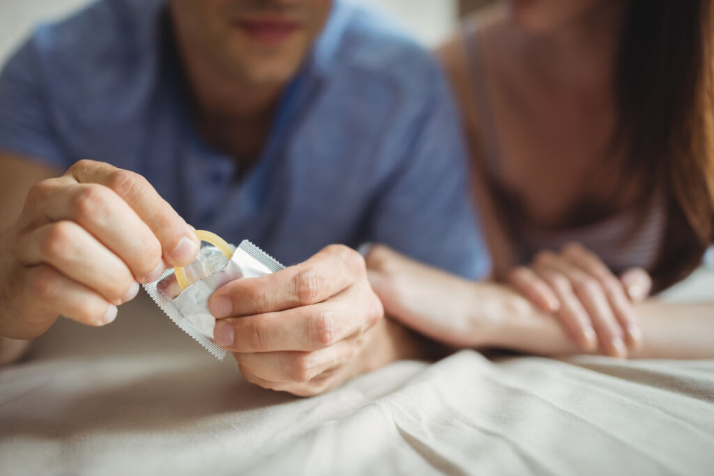 Close-up of couple with a condom on bed in the bedroom 