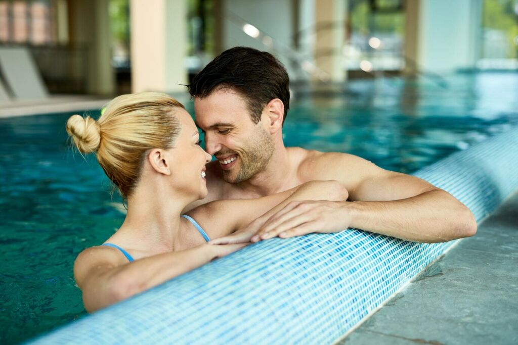 Loving couple talking face to face while being in the water of indoor swimming 